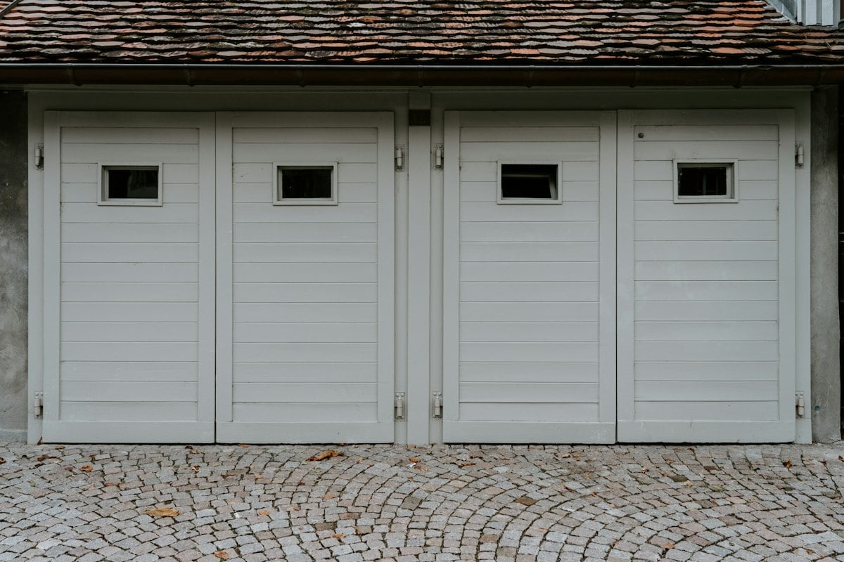 Four white wooden garage doors with small windows